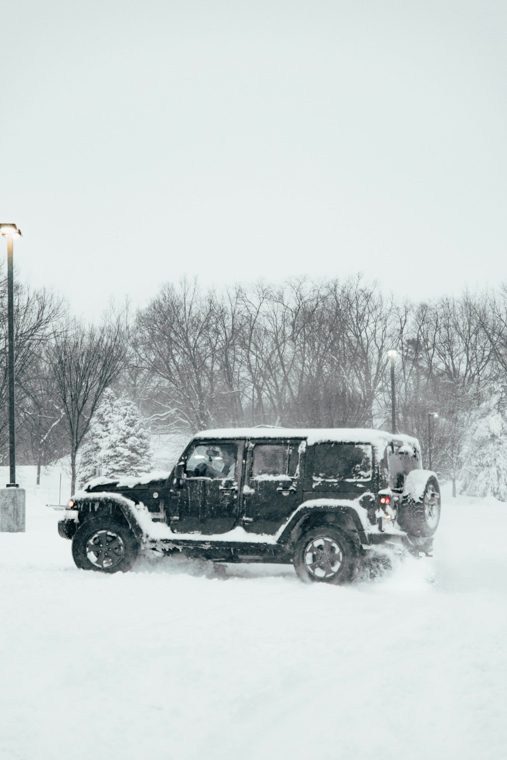 a jeep driving through the snow in a parking lot