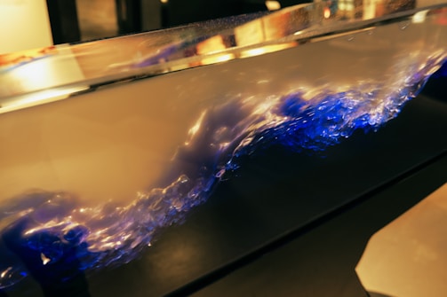 A mesmerizing display of liquid dynamics within a transparent container. The swirling fluid exhibits a captivating blend of blue and white colors, resembling a crashing wave or turbulent flow. The lighting highlights the fluid's motion, creating an artistic and dynamic visual.