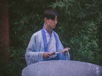 A serene spiritual guide holding a colorful ritual object in a peaceful natural setting.