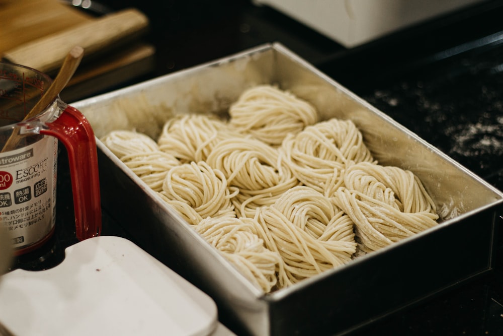 a pan filled with noodles next to a can of sauce