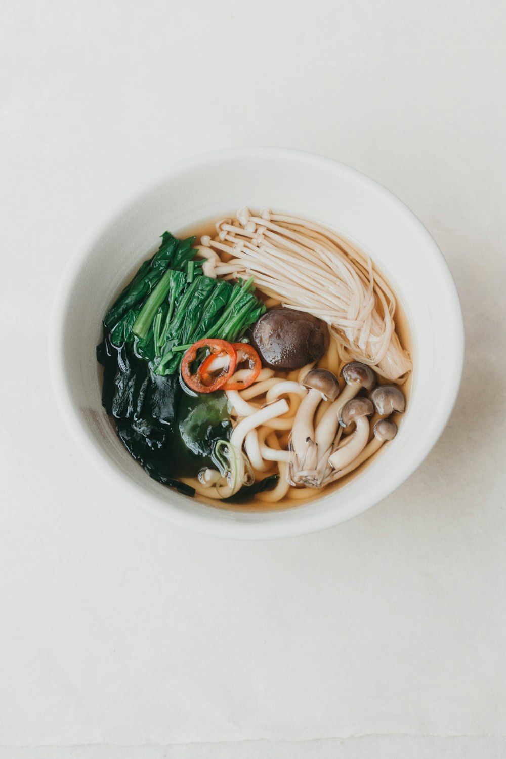 a white bowl filled with noodles and vegetables