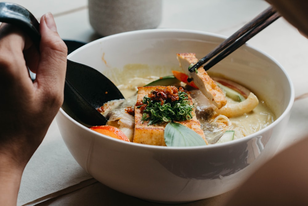 a bowl of food with chopsticks in it