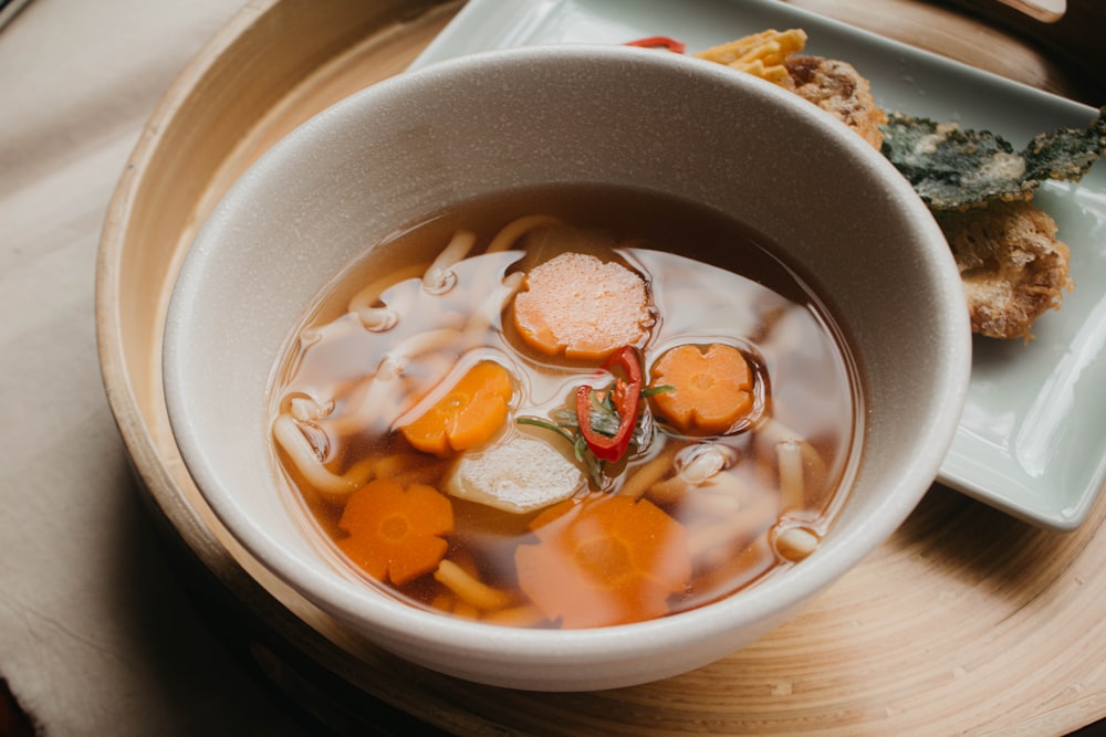 a bowl of soup with carrots and other foods