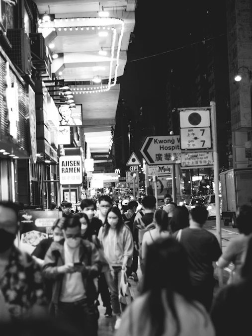 a crowd of people walking down a street next to tall buildings