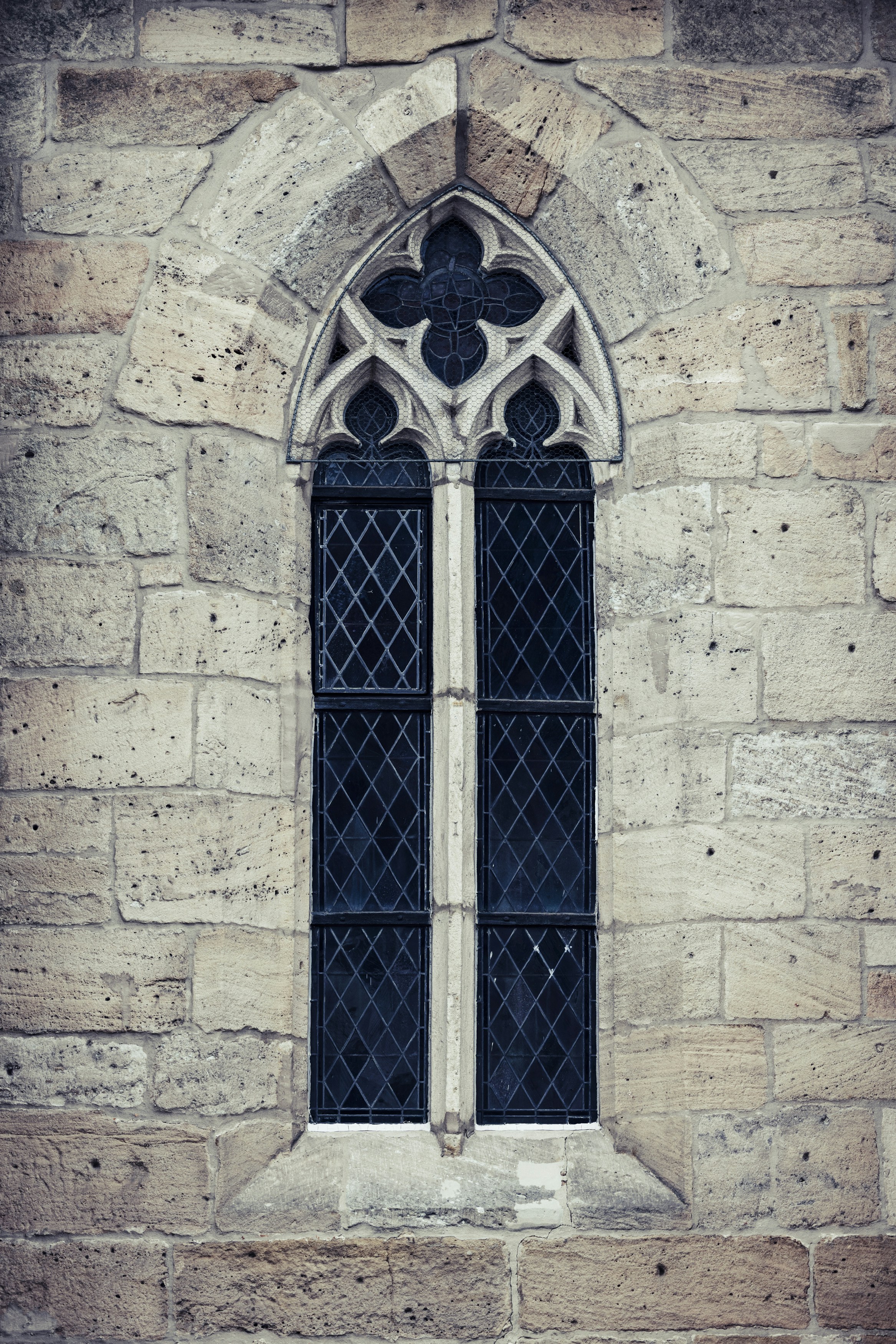 a window in a stone building with a black glass pane
