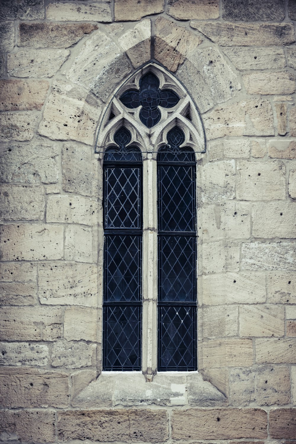 a window in a stone building with a black glass pane