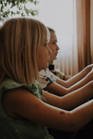 The children playing quietly in the worn-out living room with their grandmother nearby.