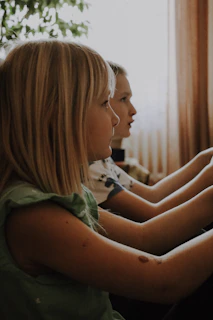 The children playing quietly in the worn-out living room with their grandmother nearby.