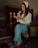 A woman smiling while reading a book in a cozy setting.
