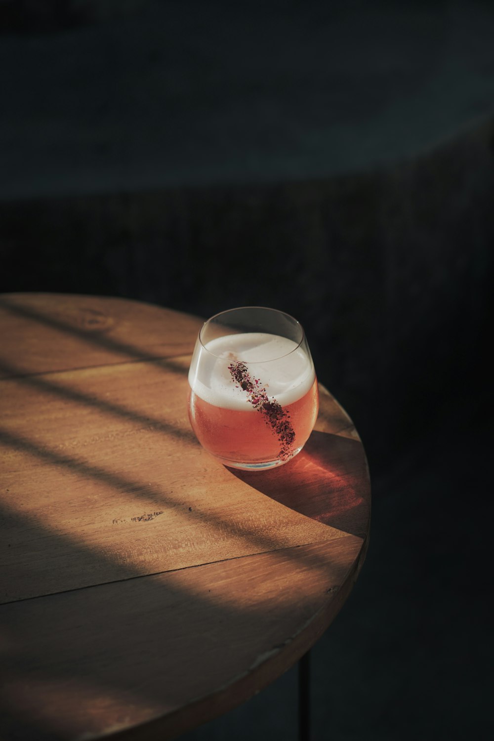 un bicchiere di vino seduto sopra un tavolo di legno