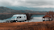 A cozy camper van parked beside a serene Scottish loch at dawn, with golf clubs leaning against the van door.