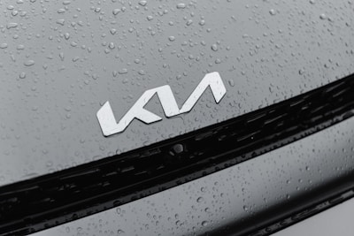 A car hood appears with water droplets scattered across it, featuring a silver logo in the center.