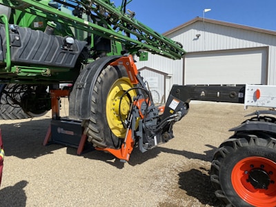 Technician repairing agricultural machinery in a rural farm setting.