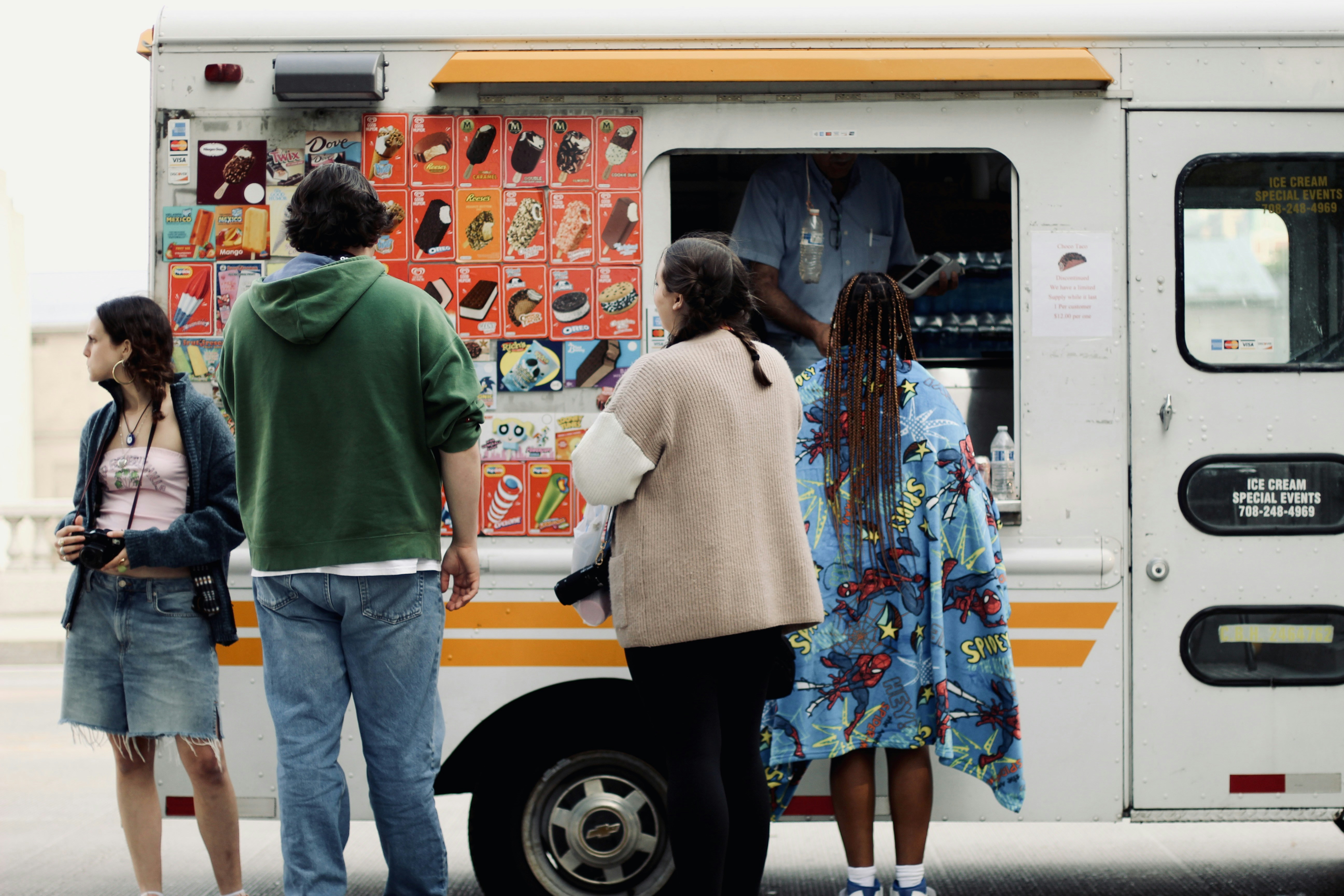 a group of people standing in front of a food truck, 