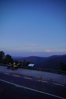 Sunset view of motorcycles lined up on a hilltop overlooking a peaceful village.