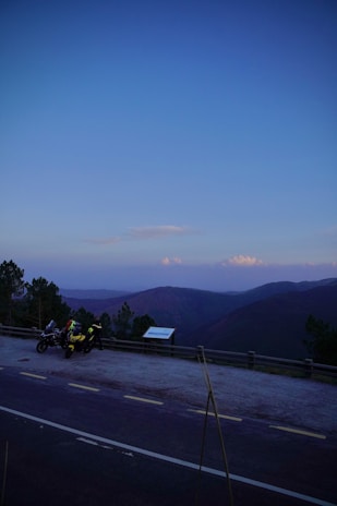 Sunset view of motorcycles lined up on a hilltop overlooking a peaceful village.