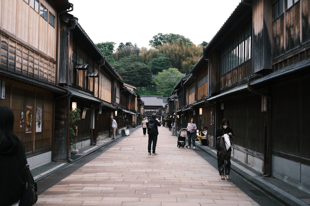 a group of people walking down a street next to tall buildings