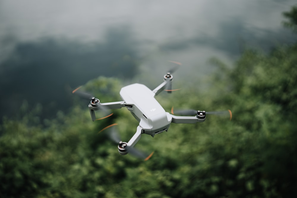 a white flying object in the air over a forest