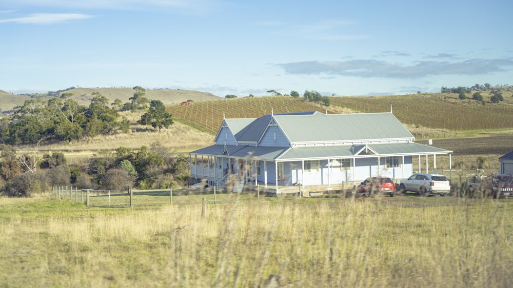 a blue house sitting in a field next to a lush green hillside