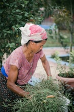 an older woman is working in a garden