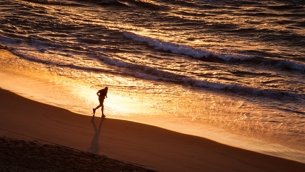 a person walking along a beach at sunset