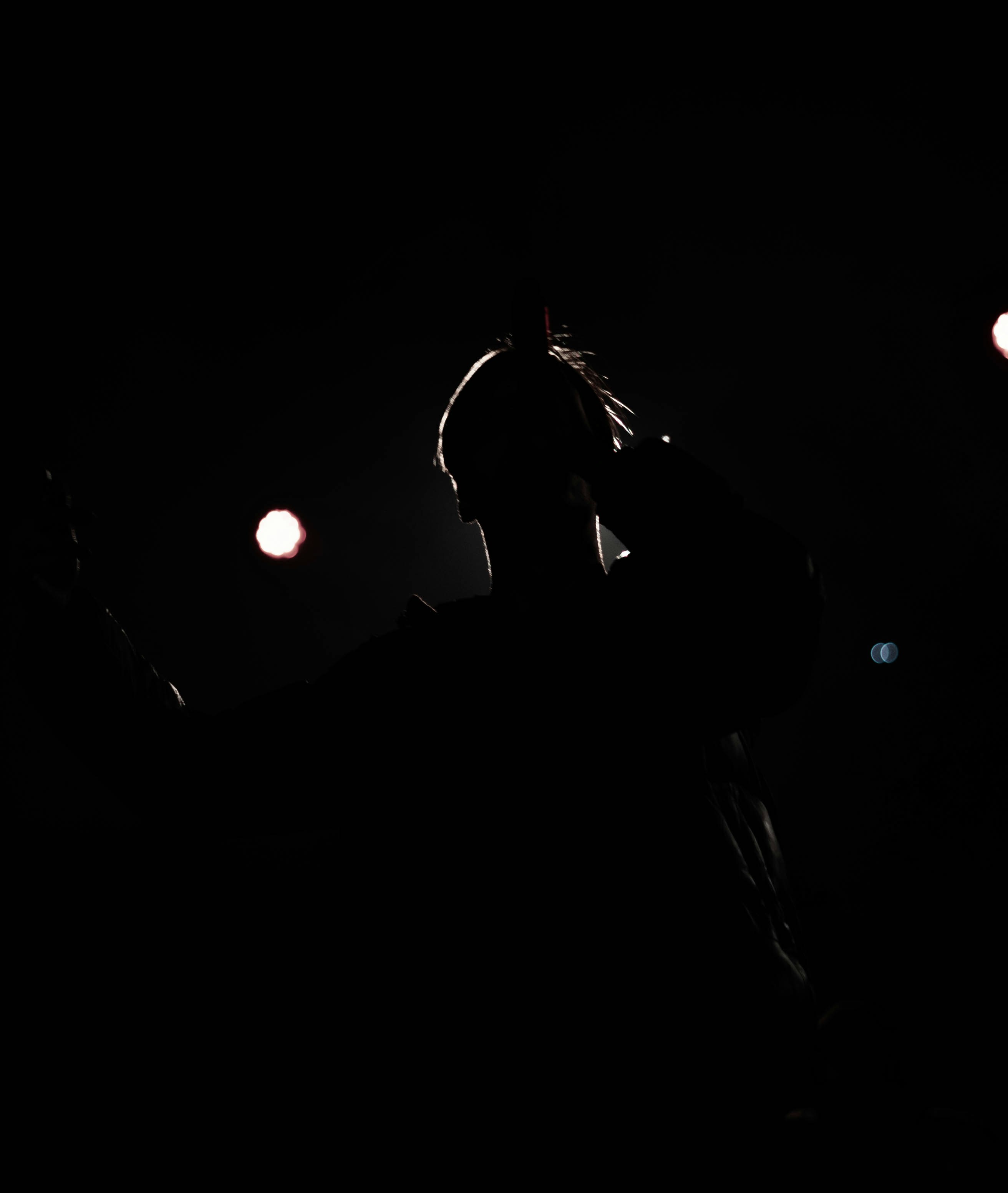 a person standing in the dark with a cell phone to their ear