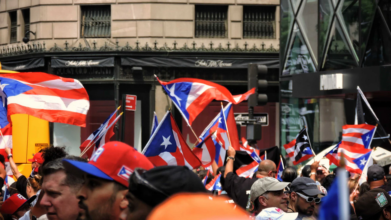 Grupo de personas en una celebración comunitaria sosteniendo banderas de Puerto Rico
