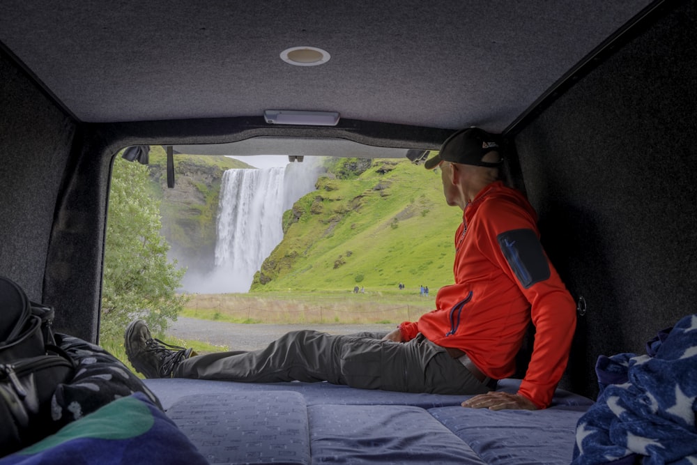 a man sitting in the back of a truck looking at a waterfall
