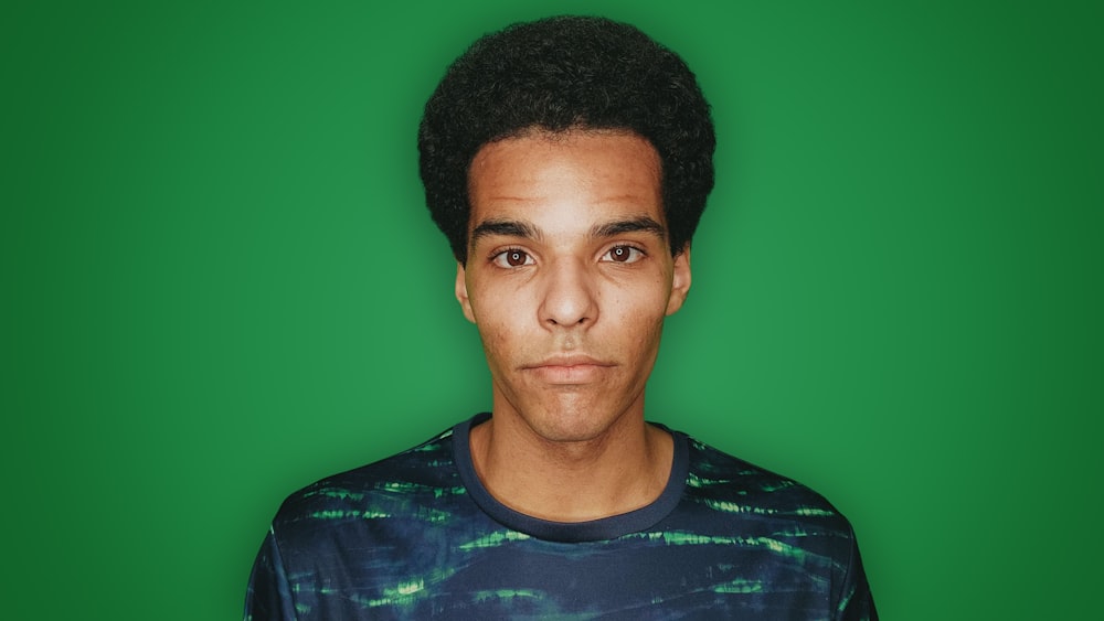 Autistic advocate staring at camera with green screen behind him