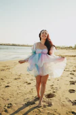 Model walking along the shore wearing a colorful summer dress from Brisaviva.