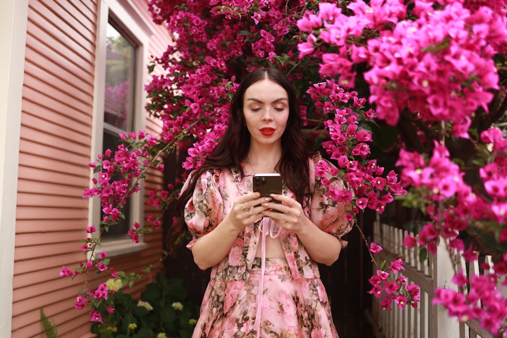 Una donna in un vestito rosa che guarda un telefono cellulare