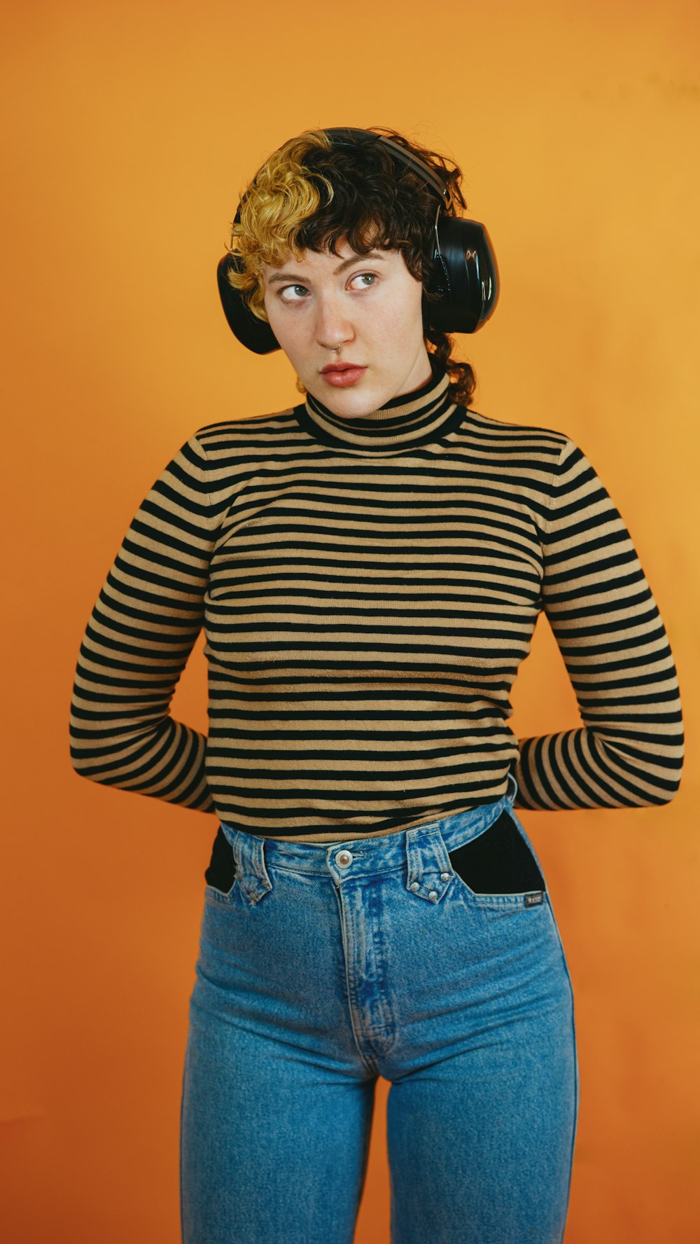 Retrato de uma pessoa autista não-binária em um ambiente de estúdio usando fones de ouvido 