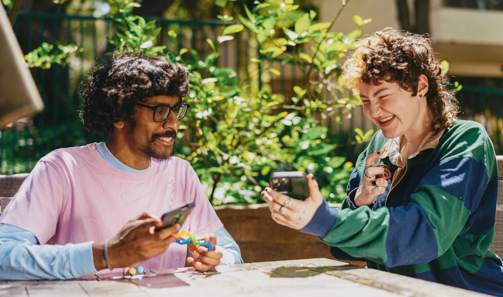 Two autistic friends sitting outside using stim toys and laughing at their phones