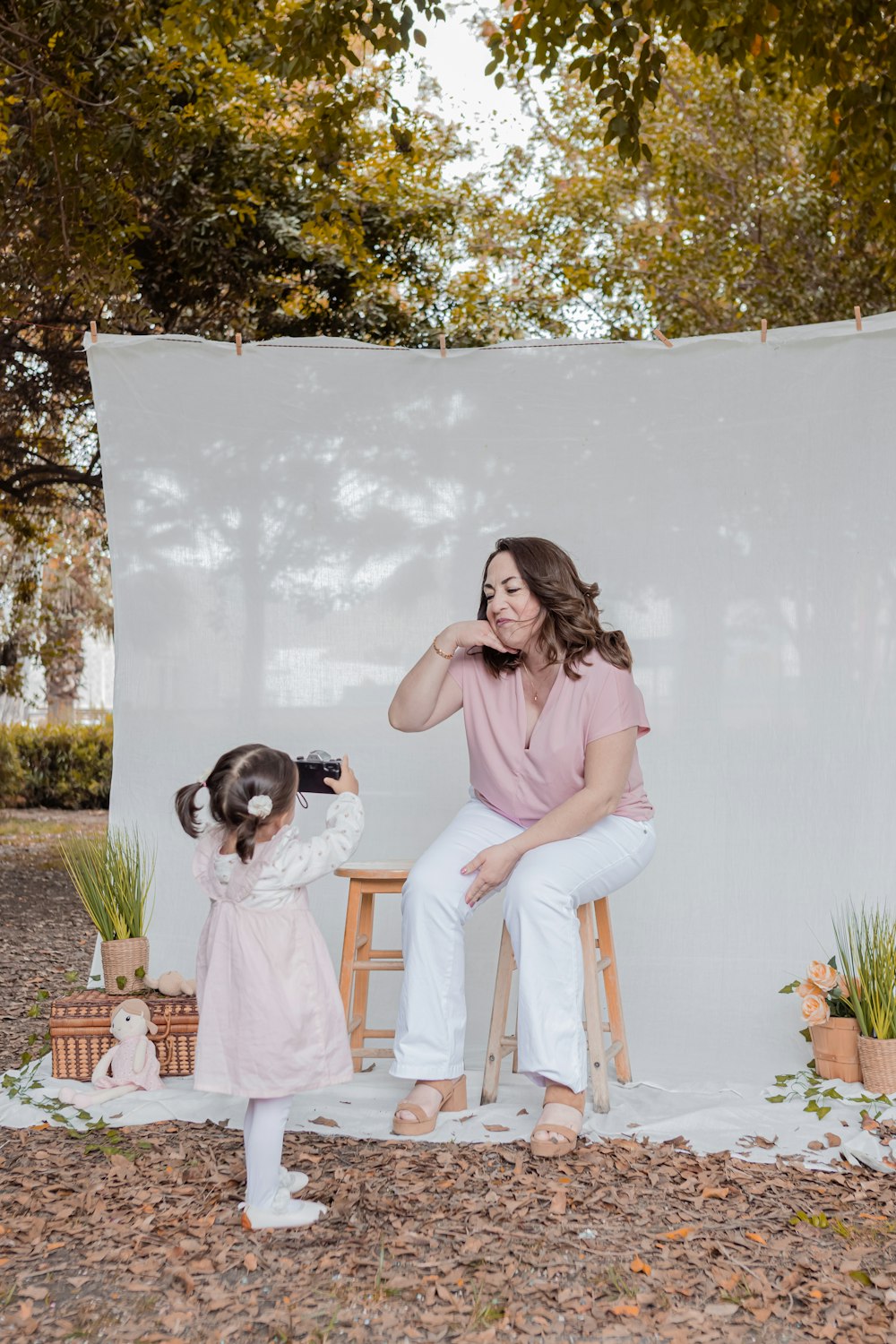 a woman sitting on a stool next to a little girl