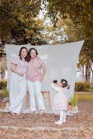 two women and a little girl standing in front of a white backdrop