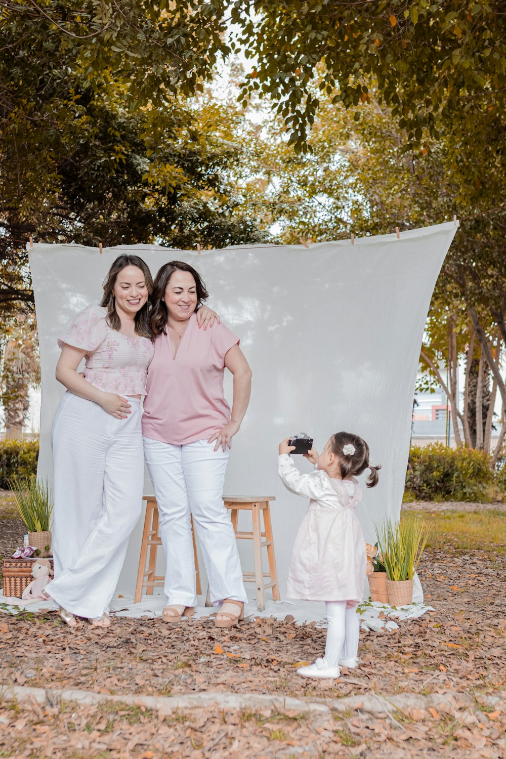 two women and a little girl standing in front of a white backdrop