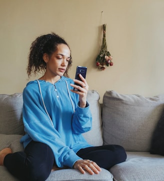 a woman sitting on a couch looking at her cell phone