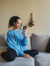 a woman sitting on a couch looking at her cell phone