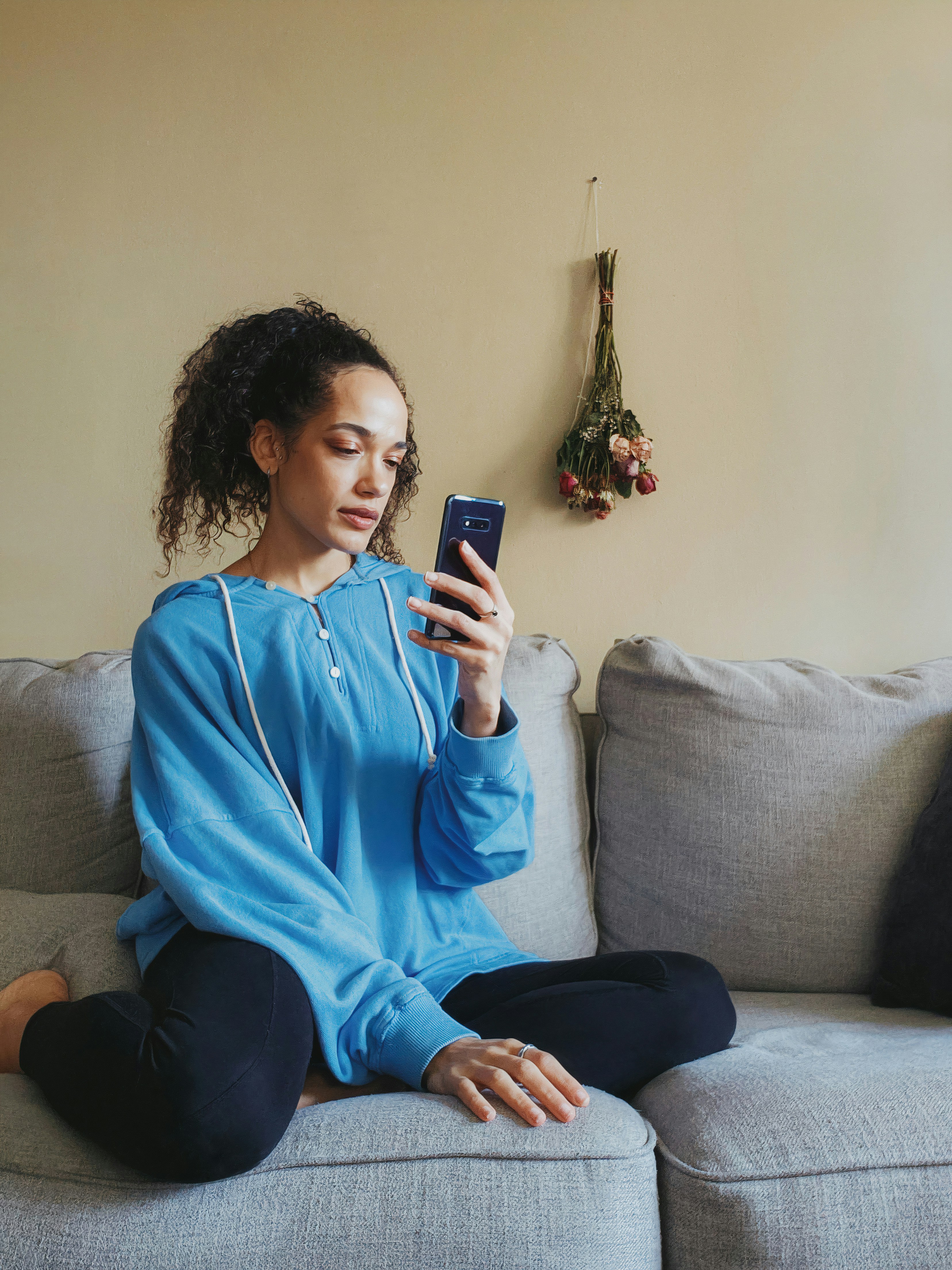 a woman sitting on a couch looking at her cell phone