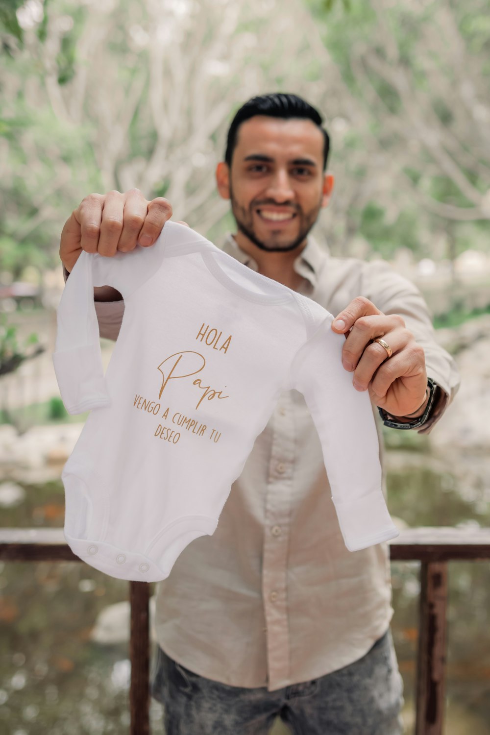 Un hombre sosteniendo una camisa blanca con letras doradas