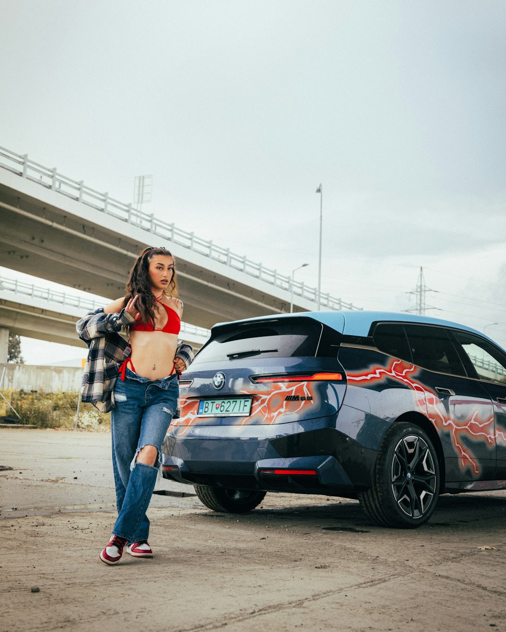 Una mujer parada junto a un coche con graffiti en él