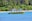 A yellow boat labeled 'SAMARA ADVENTURES' is floating on a blue body of water near a tropical shoreline lined with dense green palm trees and other vegetation.