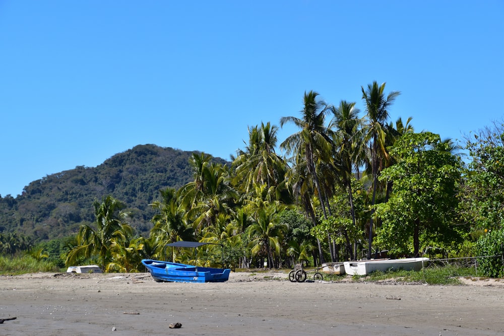 a blue boat sitting on top of a sandy beach