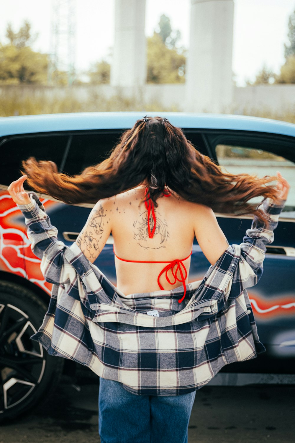 a woman with long hair standing in front of a car