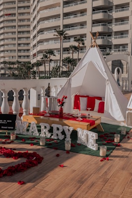 a tent set up for a party with red rose petals on the ground