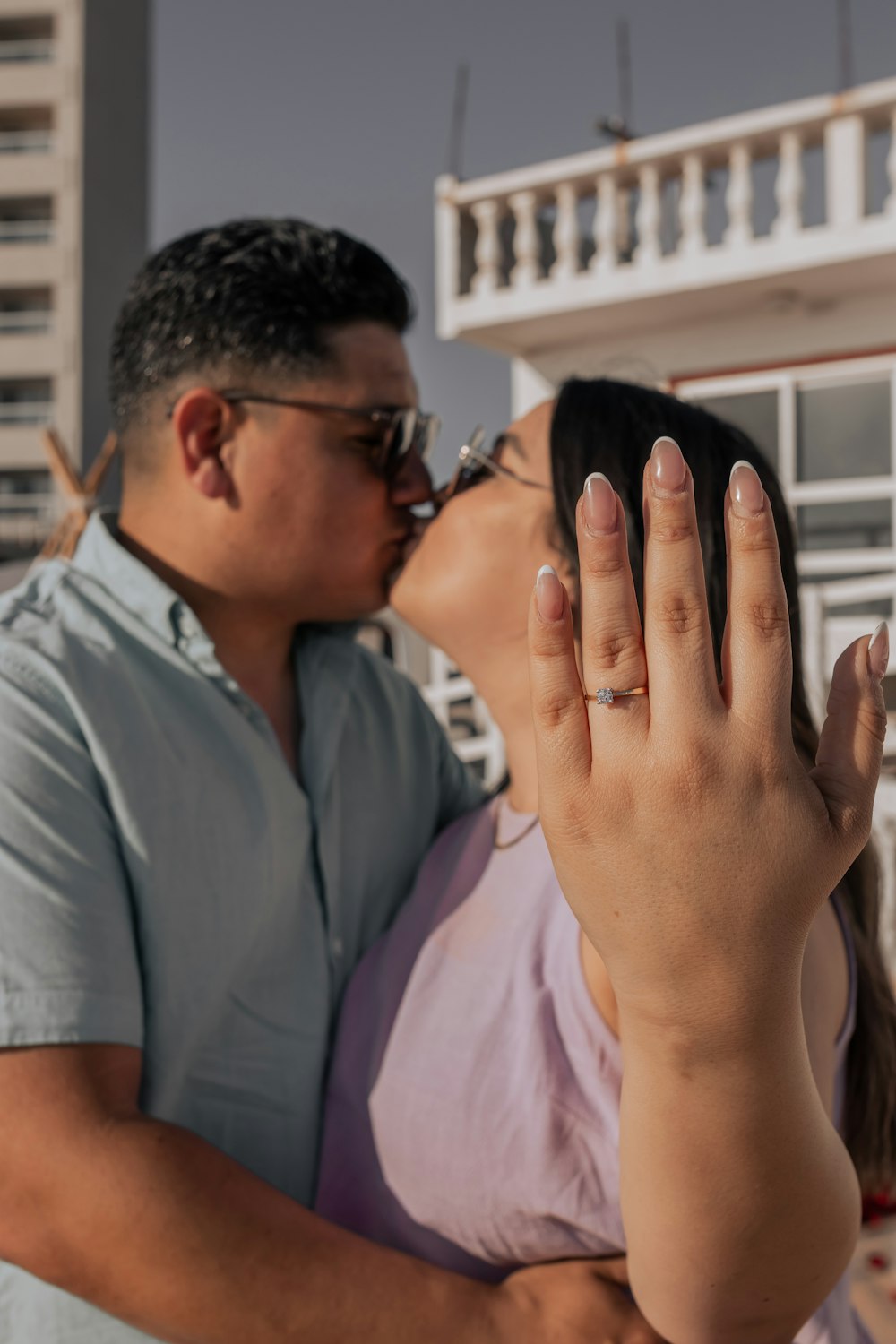 a man and a woman kissing in front of a building