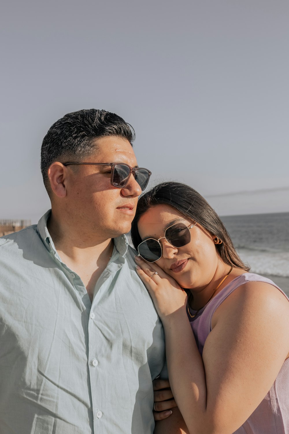 a man and woman standing next to each other near the ocean