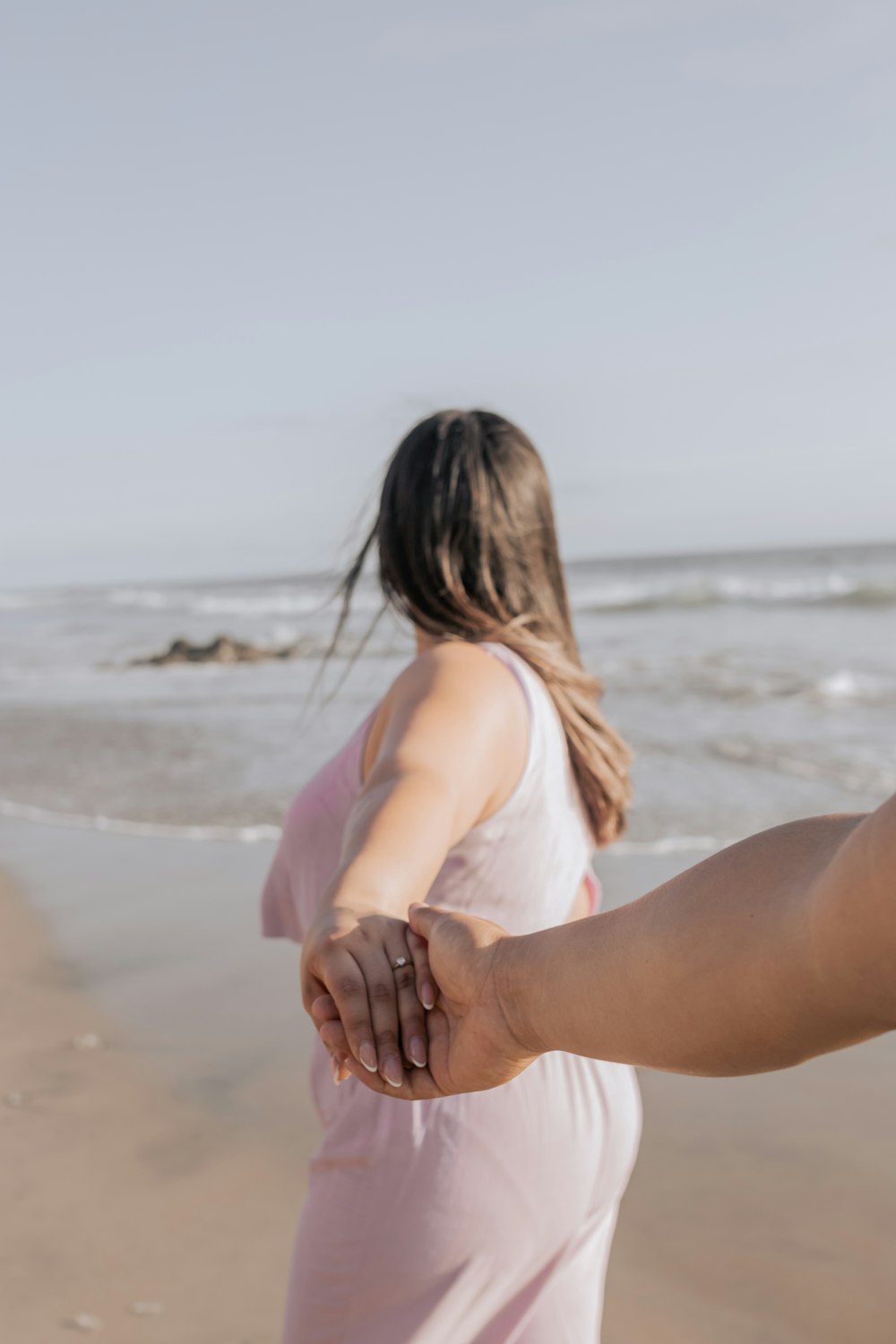 a man and a woman holding hands on the beach