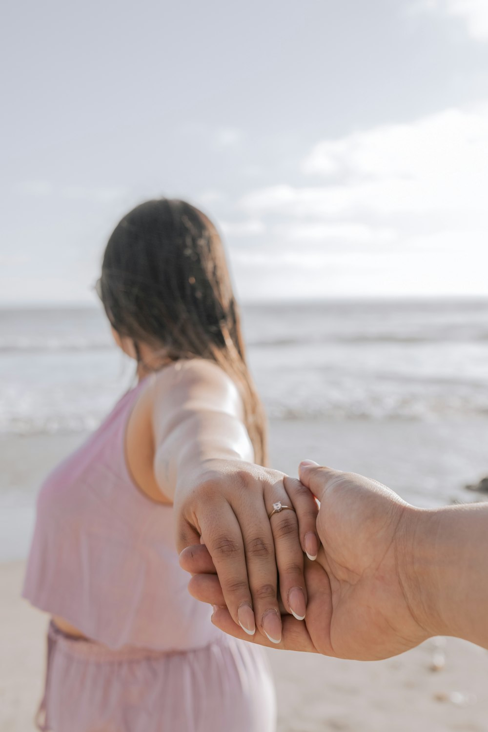 a person holding the hand of another person on a beach