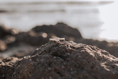 Artistic shot of a gemstone ring nestled in fine sand illuminated by golden light.